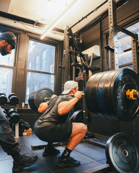 Чоловік робить присідання з важкими вагами